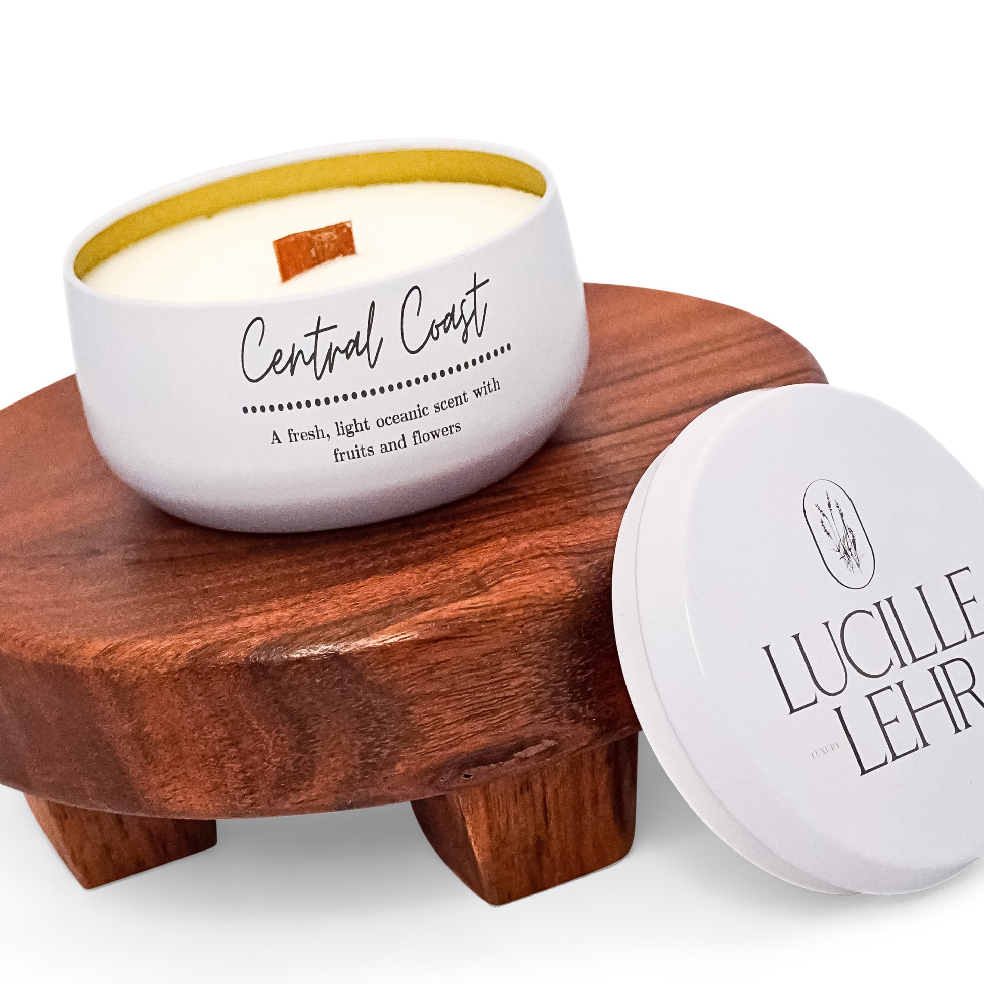 Lucille Lehr's 'Central Coast' Candle: Immerse yourself in the fresh, light oceanic aroma of the 'Central Coast' candle, featuring delicate notes of fruits and flowers. Housed in a white tin with a crackling wooden wick, this candle sits gracefully on a wooden stand, bringing a refreshing coastal ambiance to any room.