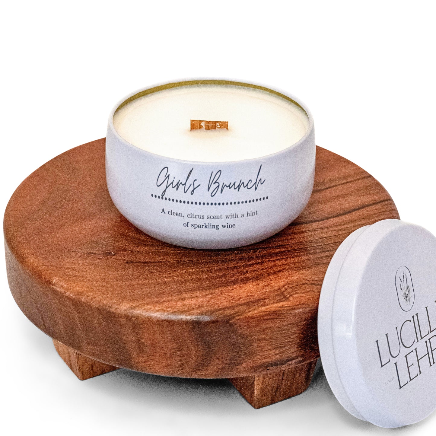 Lucille Lehr's 'Girls Brunch' Candle: Bring a refreshing touch to your space with the 'Girls Brunch' candle, offering a clean citrus fragrance with a hint of sparkling wine. Housed in a white tin with a wooden wick, it rests on a stylish wooden stand, adding a cozy and vibrant ambiance perfect for any occasion.