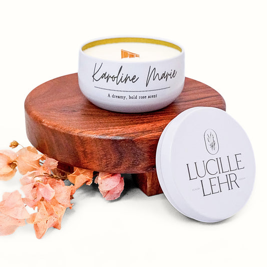 Lucille Lehr's 'Karoline Marie' Candle: Embrace the luxurious, bold rose fragrance of the 'Karoline Marie' candle, beautifully packaged in a white tin with a wooden wick for a soothing crackling sound. Set on a wooden stand and accented with soft pink dried florals, this candle adds a warm and elegant touch to any space.