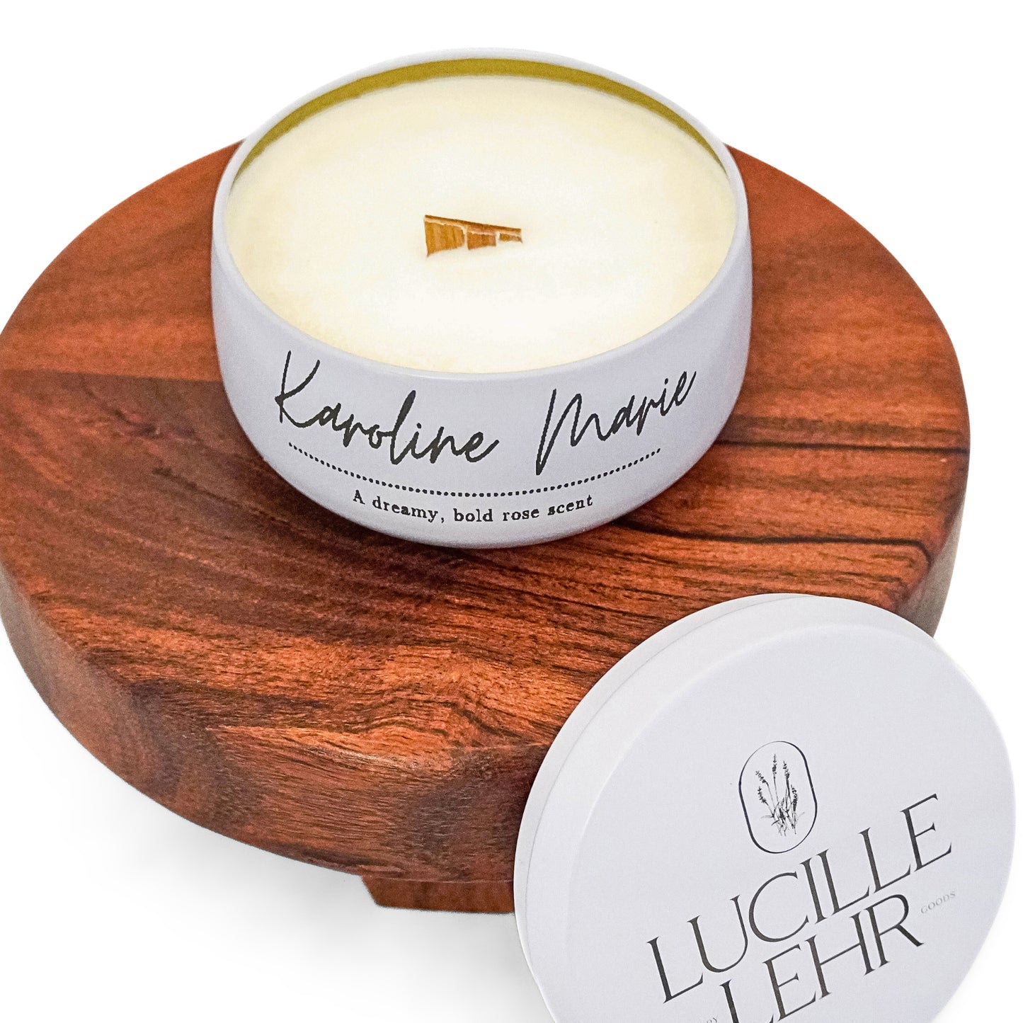 Lucille Lehr's 'Karoline Marie' Candle: Delight in the bold, dreamy rose scent of the 'Karoline Marie' candle, presented in a stylish white tin with a wooden wick that provides a soft crackling ambiance. Set on a wooden stand, this candle brings a touch of floral elegance and warmth to any setting.