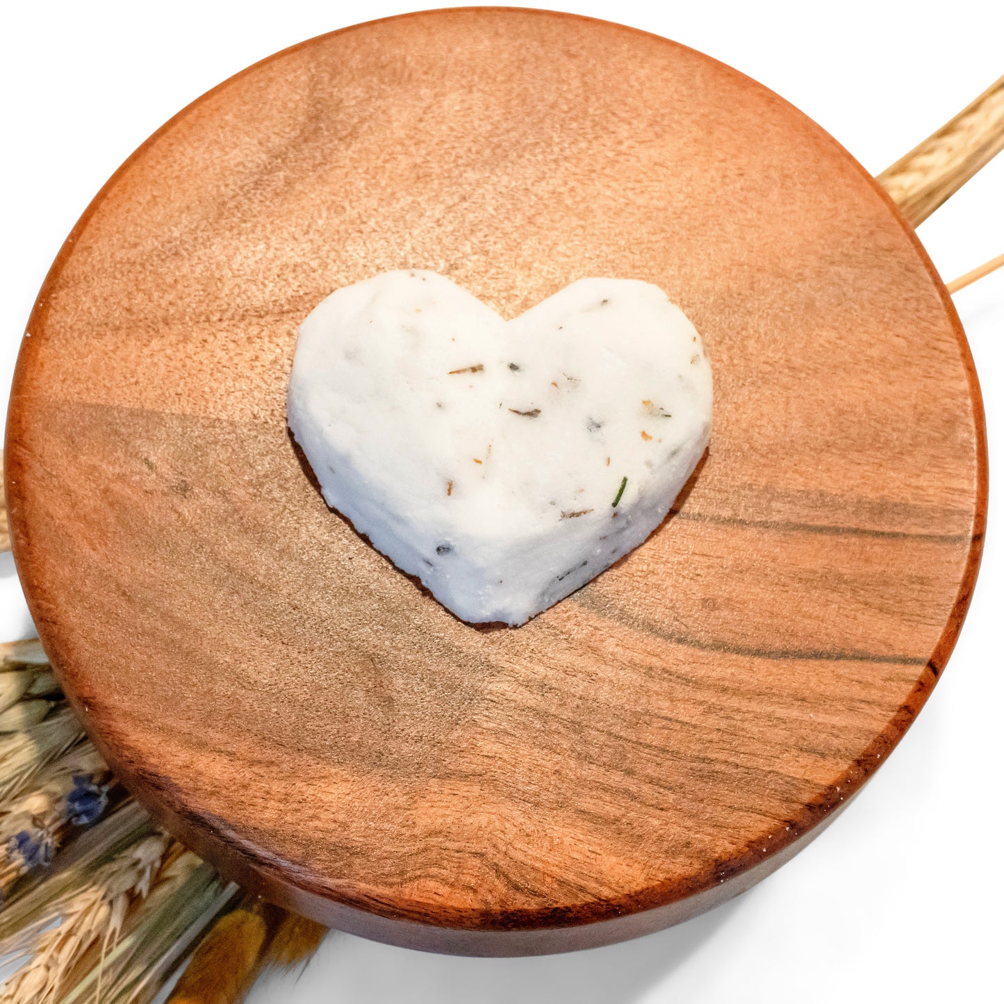 Lucille Lehr's Heart-Shaped Lavender Rose Bath Bomb: Displayed on a rustic wooden stand, this heart-shaped bath bomb is infused with lavender and rose essence, offering a relaxing, petal-free bath experience. Crafted to dissolve smoothly, it releases a gentle fragrance for a soothing, spa-like atmosphere.