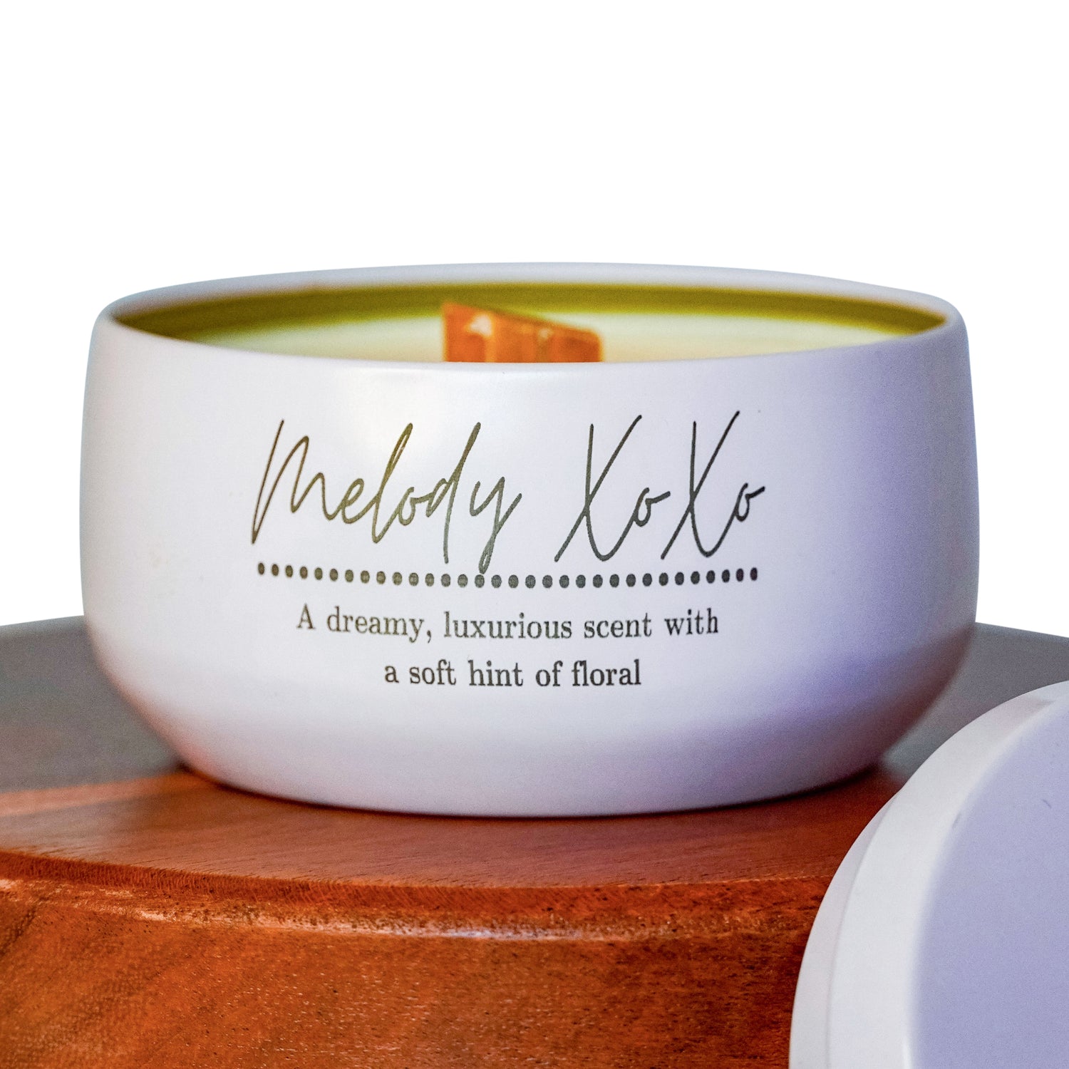 Lucille Lehr's 'Melody XoXo' Candle Close-up: This white tin candle features the 'Melody XoXo' label, showcasing a dreamy, luxurious scent with a soft floral hint.