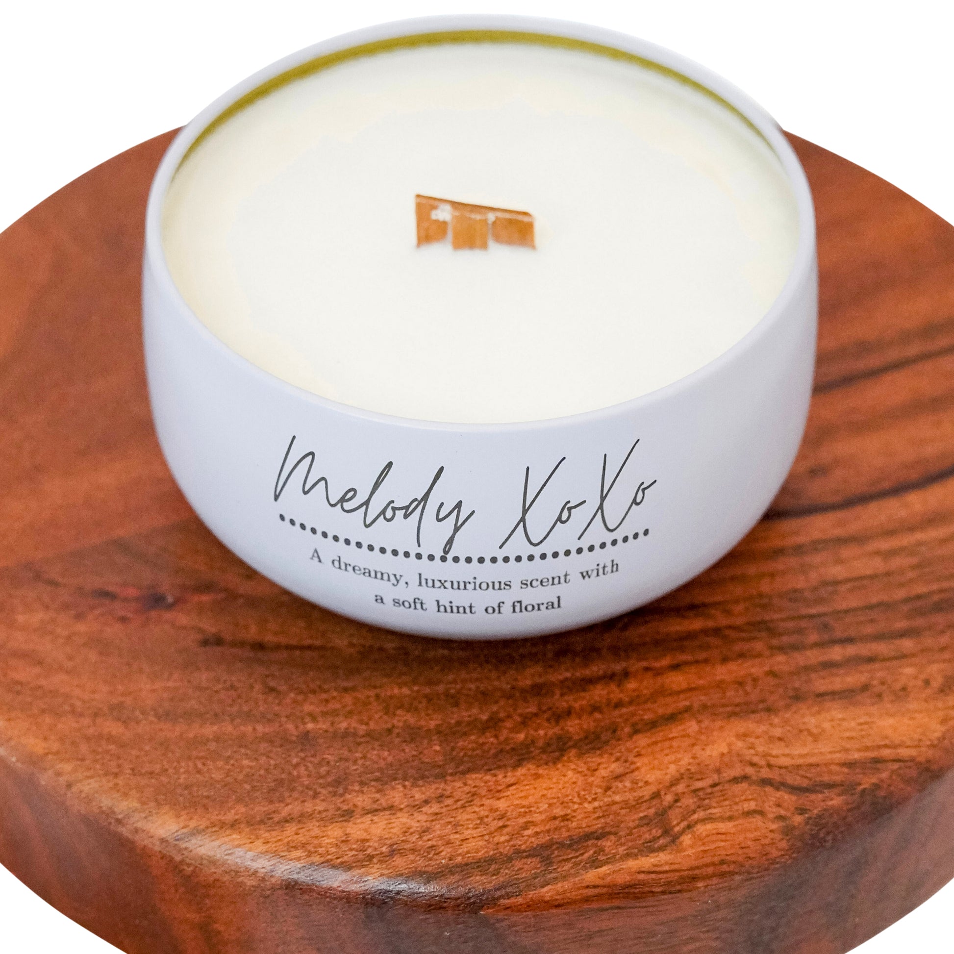 Close-up of Lucille Lehr's 'Melody XoXo' Candle: Showcasing a dreamy, luxurious scent with a soft floral hint, this candle is presented in an elegant white tin with a wooden wick that crackles gently when lit. Perfect for adding warmth and sophistication to any space.