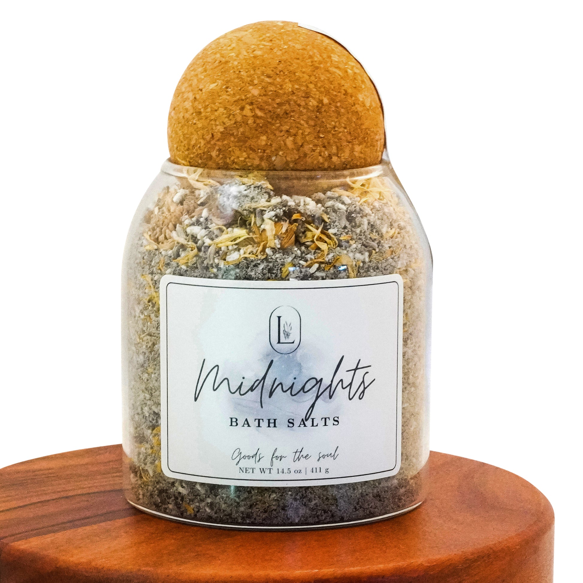 Lucille Lehr's 'Midnights' Bath Salts: Unwind and rejuvenate with the 'Midnights' bath salts, a luxurious blend designed to soothe the soul. Infused with botanical elements and calming minerals, this bath salt is elegantly packaged in a clear jar with a natural wooden sphere lid, adding a touch of tranquility to your nighttime bath ritual.