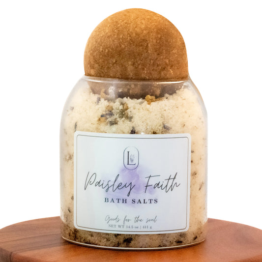 Lucille Lehr's 'Paisley Faith' Bath Salts: Indulge in a soul-soothing experience with these luxurious bath salts, featuring a blend of calming lavender and natural minerals. Beautifully presented in a clear jar with a wooden sphere lid, 'Paisley Faith' bath salts offer a touch of elegance and serenity to your bath ritual.